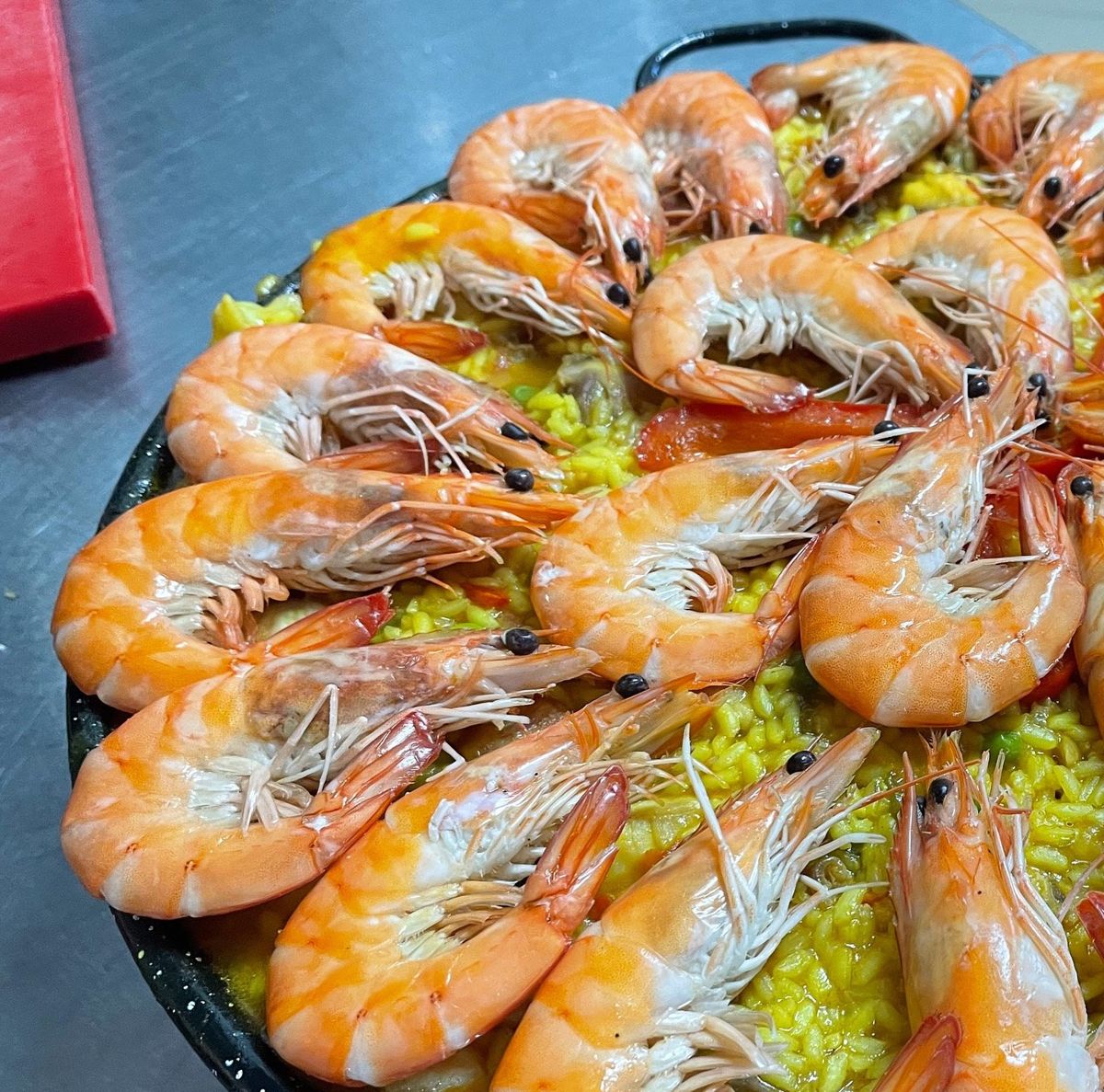 Paelheira com arroz amarelo coberto de camarões inteiros